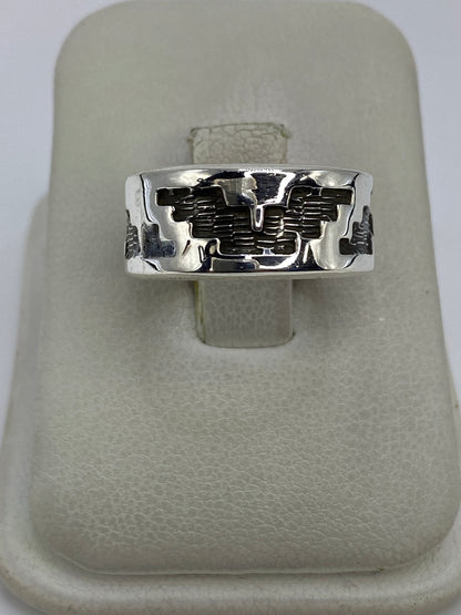 Anillo de plata repujado con diseño geométrico prehispánico en la mano de una persona