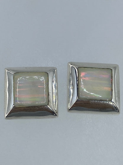 Aretes de opalo de fuego mostrando tonos rojos, naranjas y verdes bajo la luz