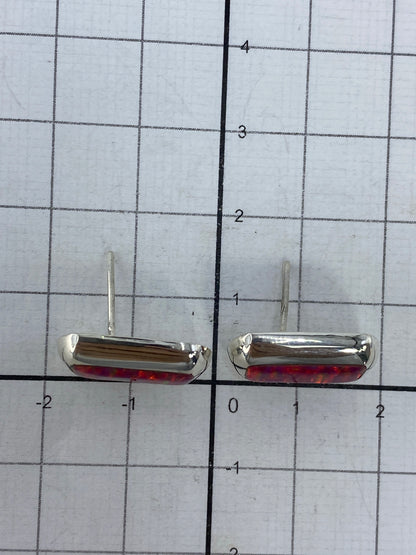Aretes en uso, vista lateral del ópalo de fuego rosa brillando