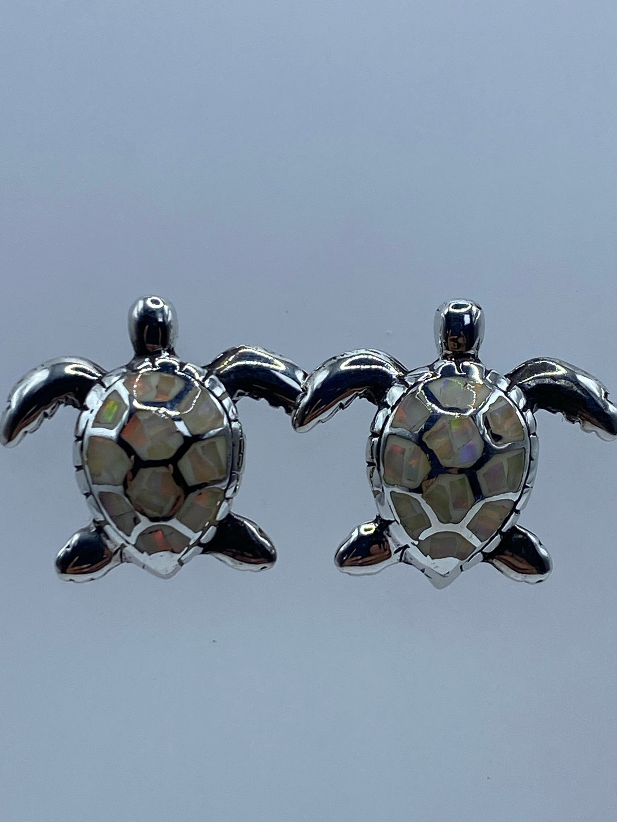 Los dos aretes juntos mostrando el tamaño y los reflejos cálidos del ópalo