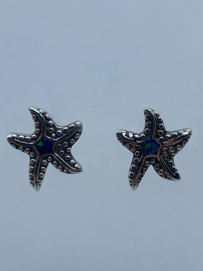 Par de aretes de plata en forma de estrella de mar con ópalo de fuego azul en el centro