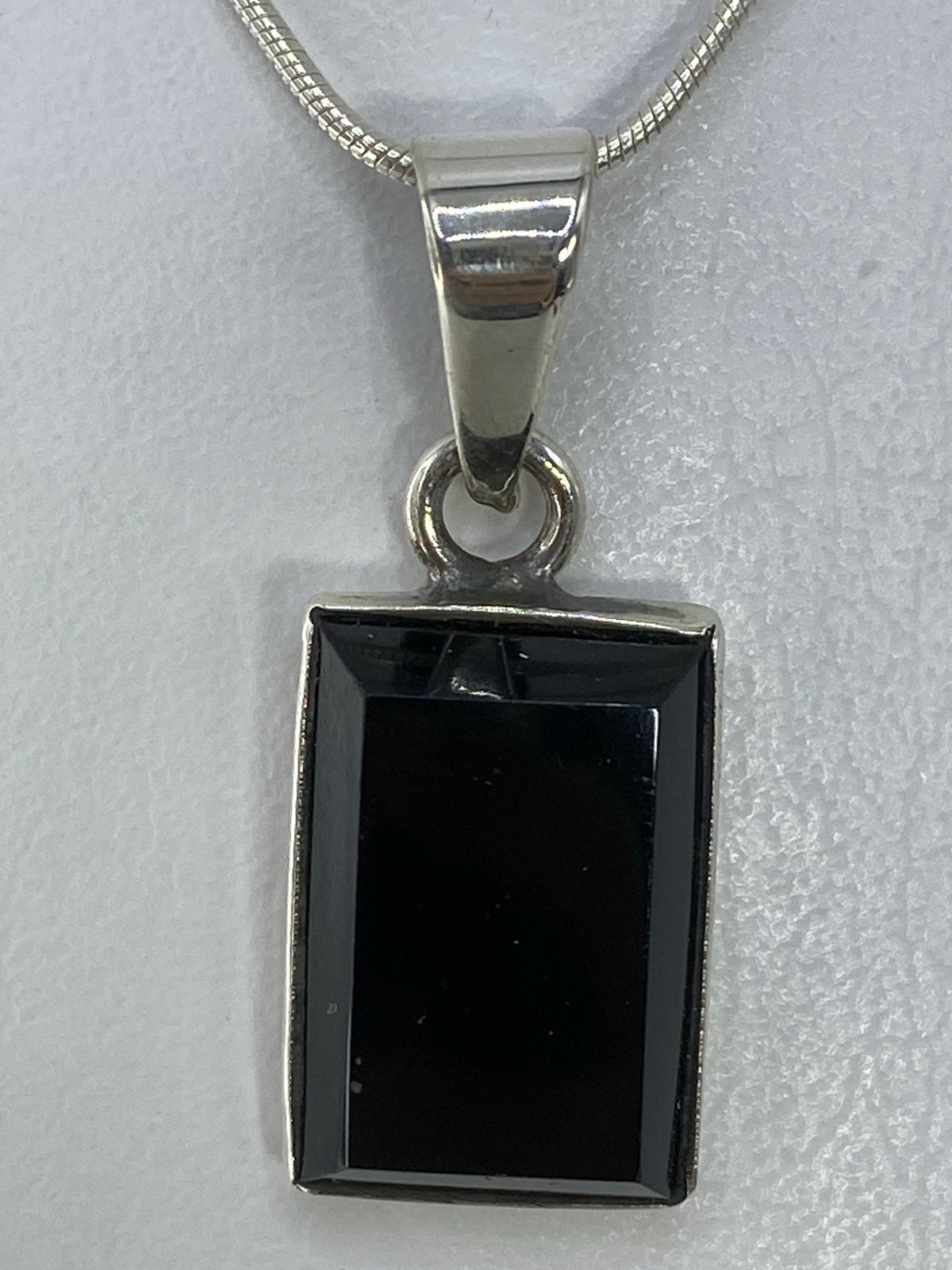 Dije rectangular de plata 950 con piedra negra engastada, sobre cadena de plata
