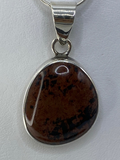 Dije de plata 950 con piedra multicolor engastada, colgando de una cadena plateada