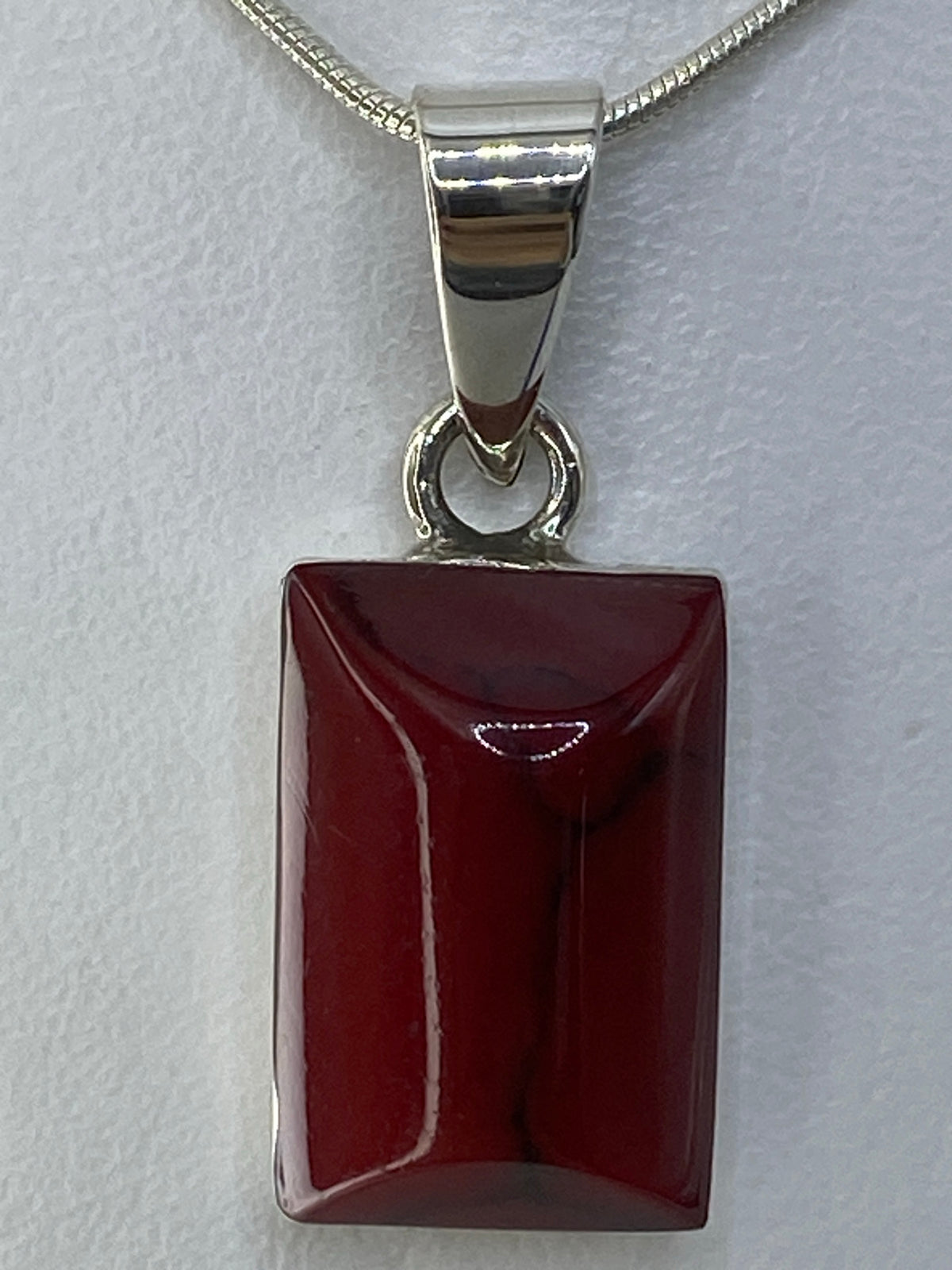 Detalle frontal del dije mostrando la incrustación de piedra roja pulida