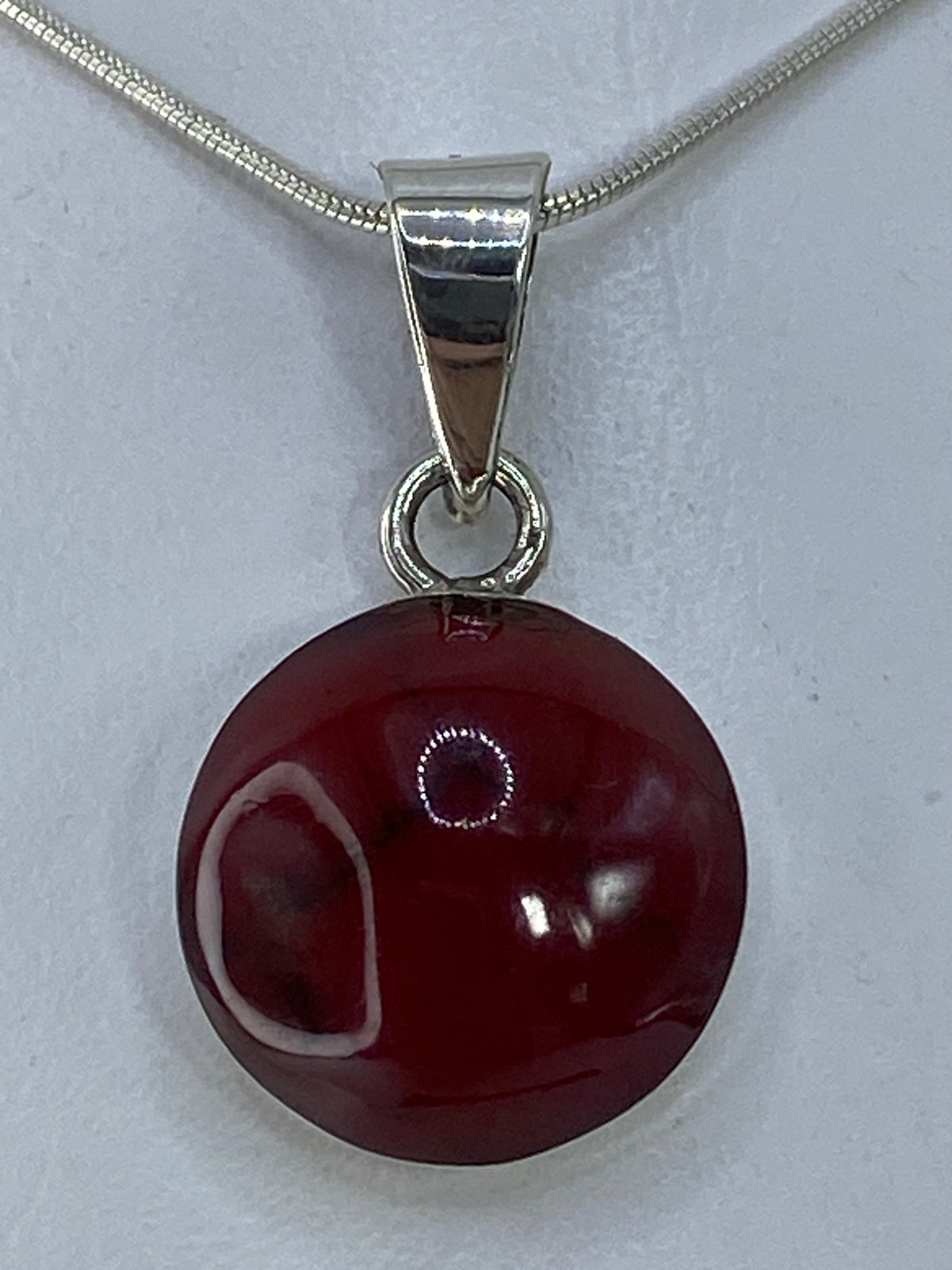 Dije de plata 950 con piedra roja redonda, colgado de cadena serpentín