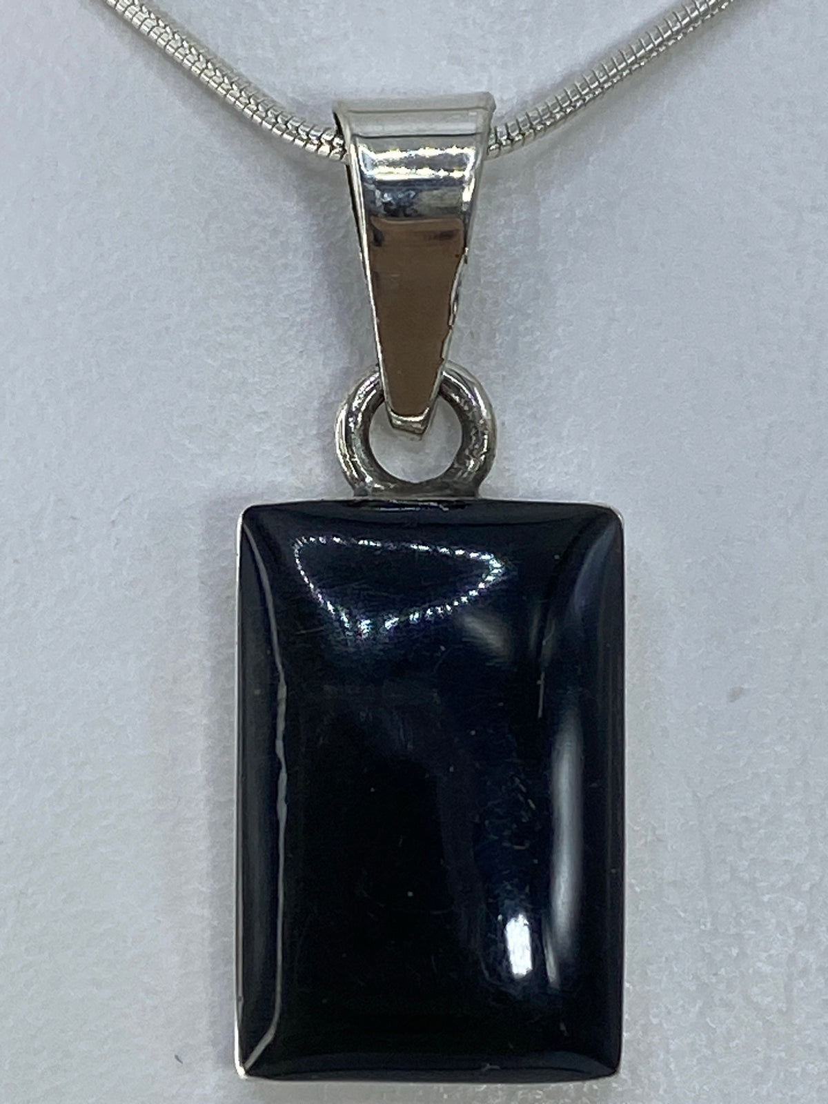 Detalle lateral del dije de plata 950 con engaste limpio y ónix pulido