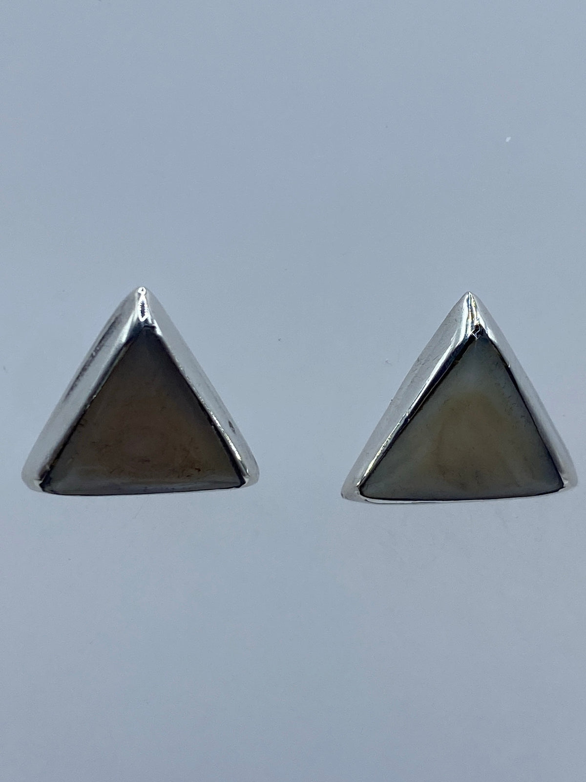 Vista frontal del par de aretes triangulares con perla blanca lechosa