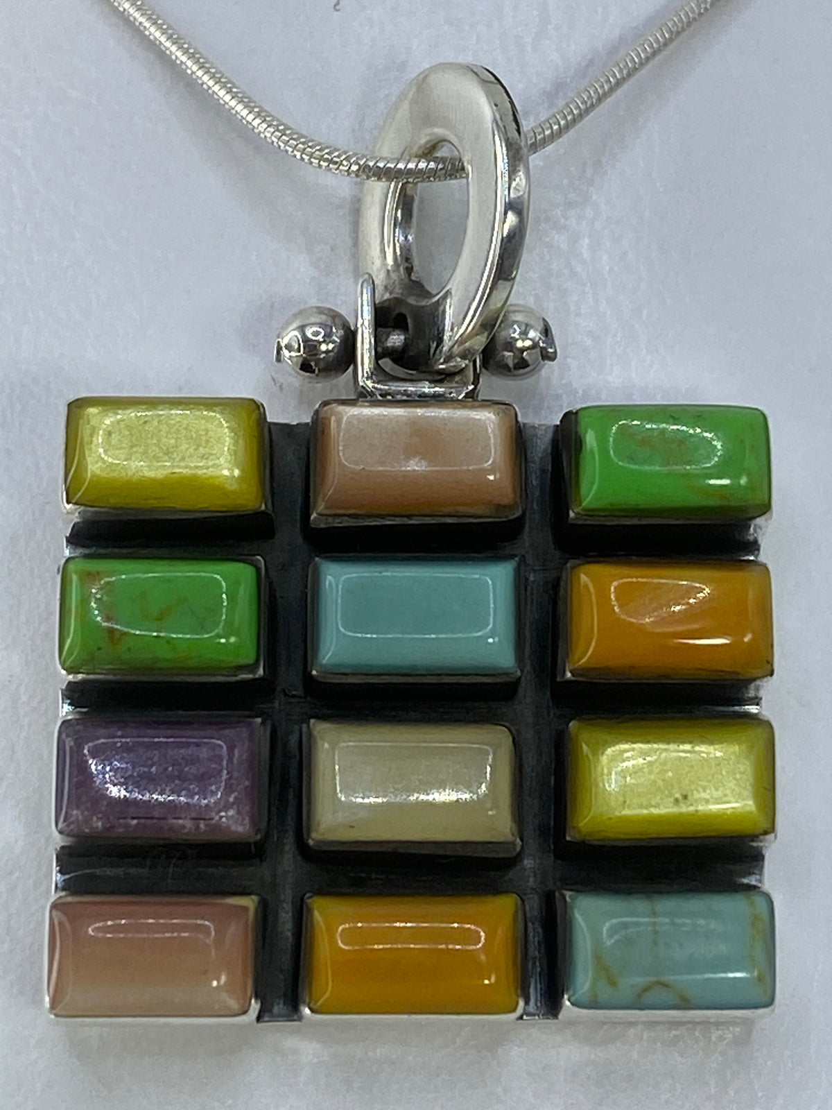 Dije de plata 925 con piedras multicolor engastadas a mano, detalle de la técnica