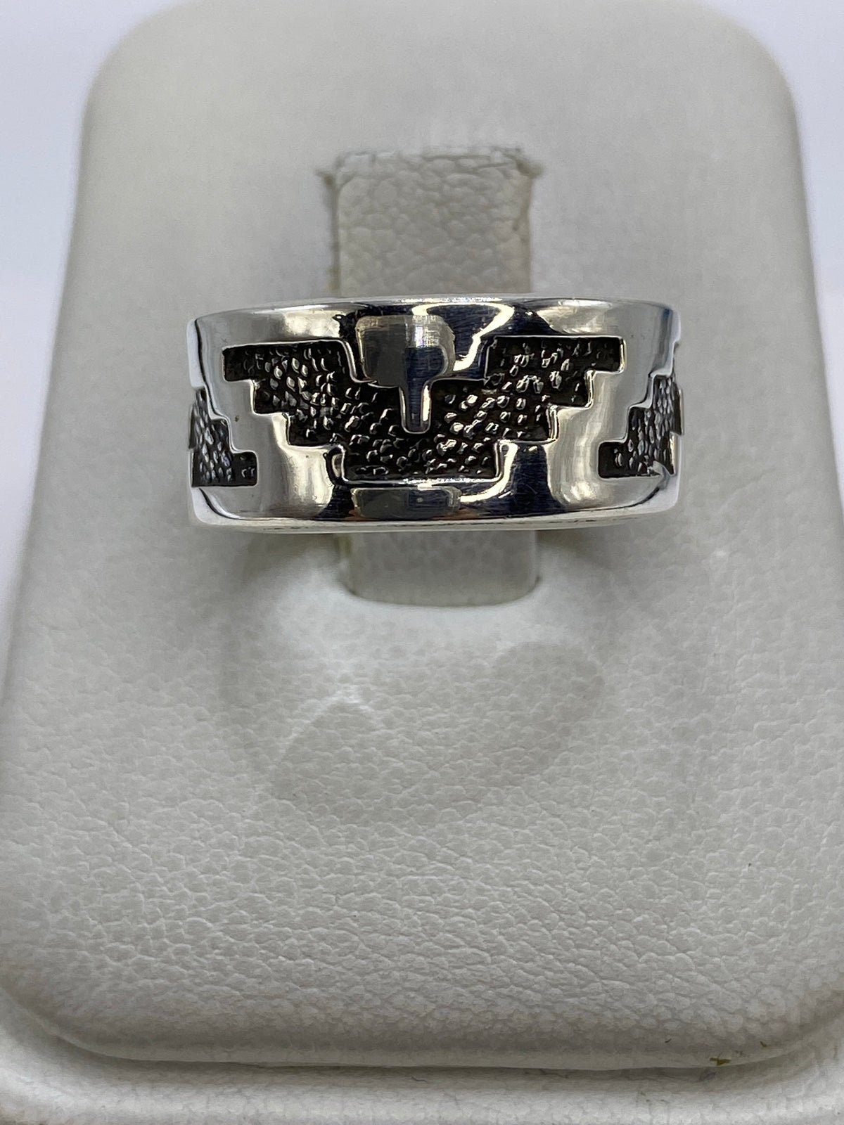 Anillo de plata repujado con motivos prehispánicos, vista frontal sobre fondo blanco