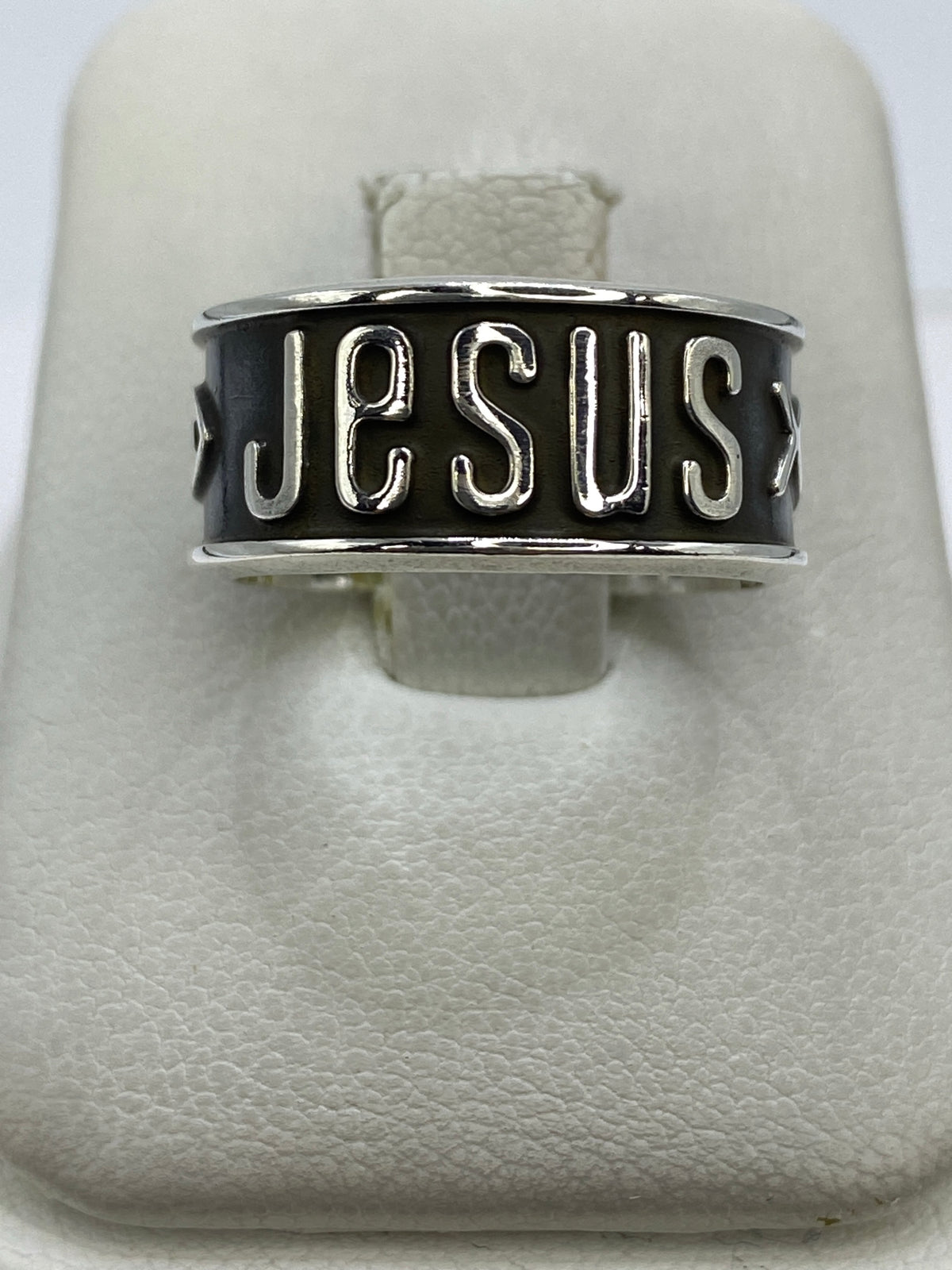 Anillo de plata repujado con mensaje JESUS en la banda, visto de frente
