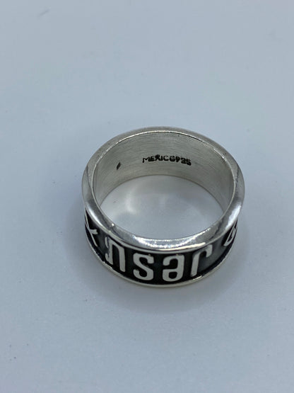 Anillo puesto en dedo mostrando el mensaje JESUS en relieve brillante