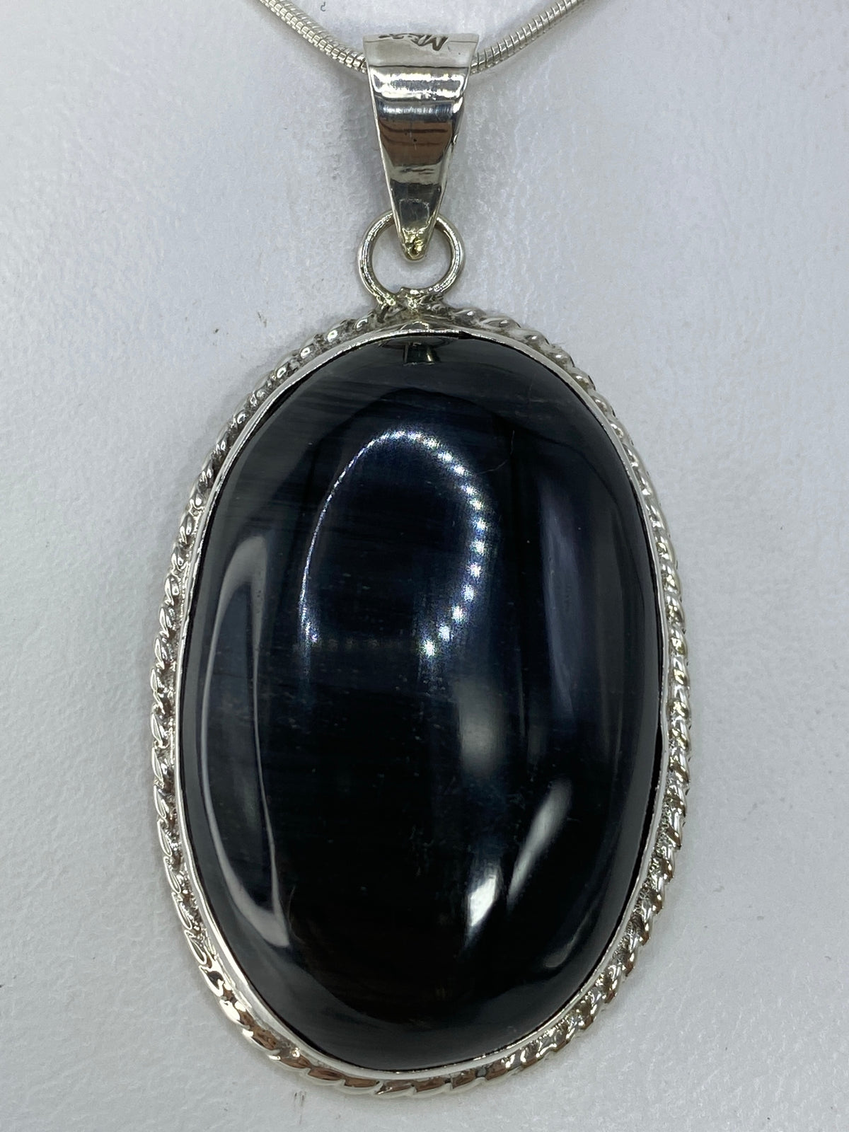 Dije de plata 950 con onix negro pulido, colgando en cadena serpentina