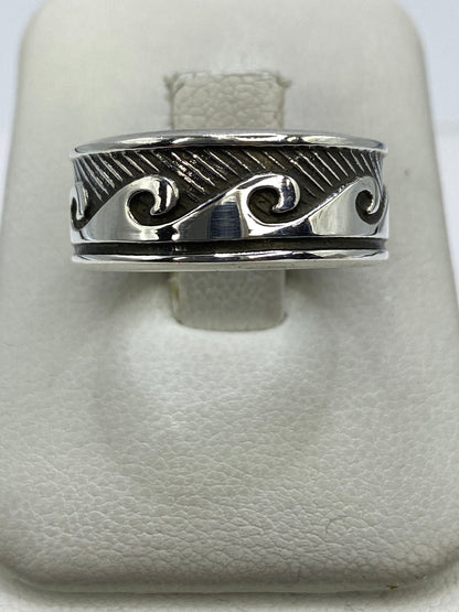 Anillo de plata repujado con ondas fluidas en la mano de una persona