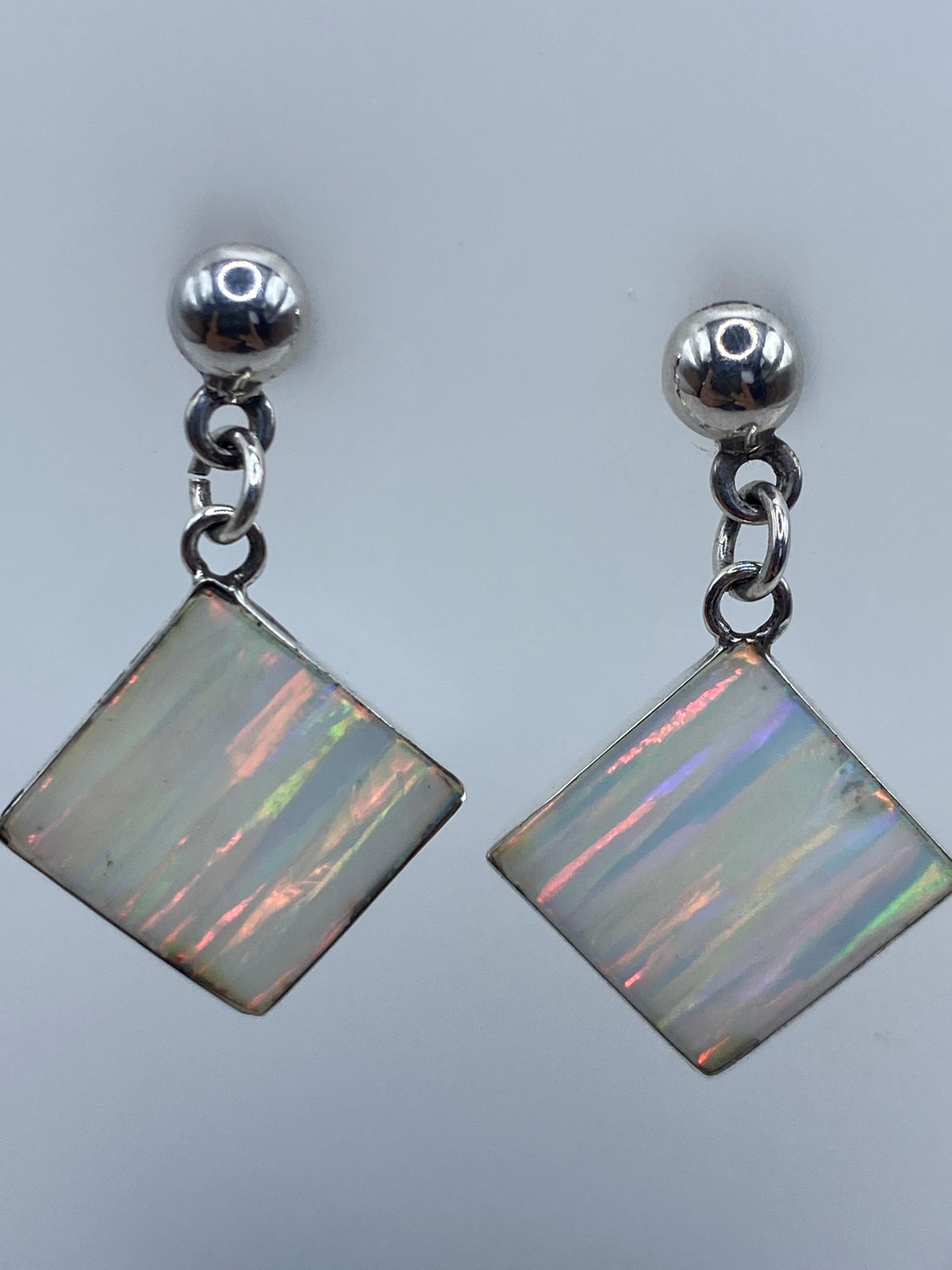 Detalle cercano del Ópalo de Fuego en los aretes reflejando naranja y verde