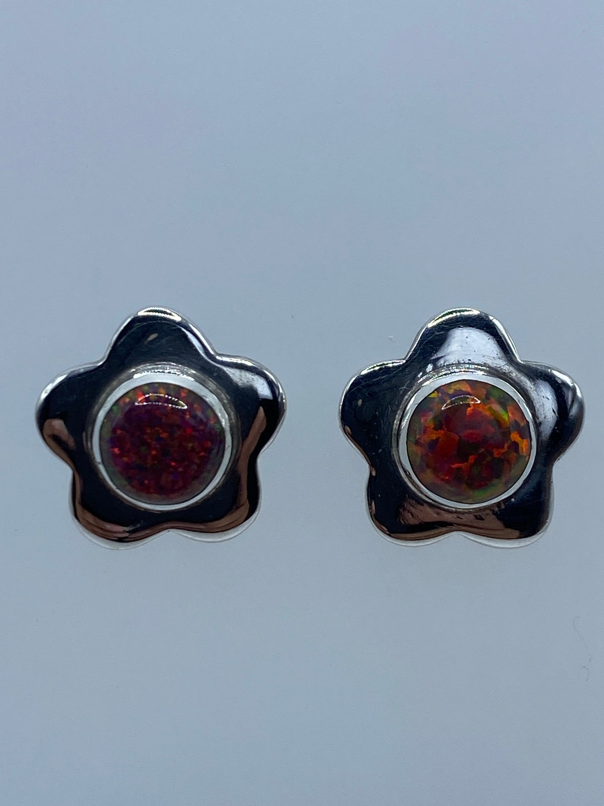 Par de aretes de plata 950 con ópalo de Fuego multicolor en forma de flor sobre fondo gris