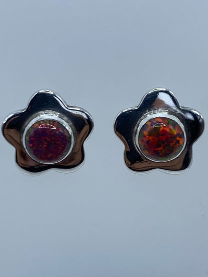 Detalle frontal de los aretes mostrando el ópalo de Fuego con tonos rojo, naranja y amarillo