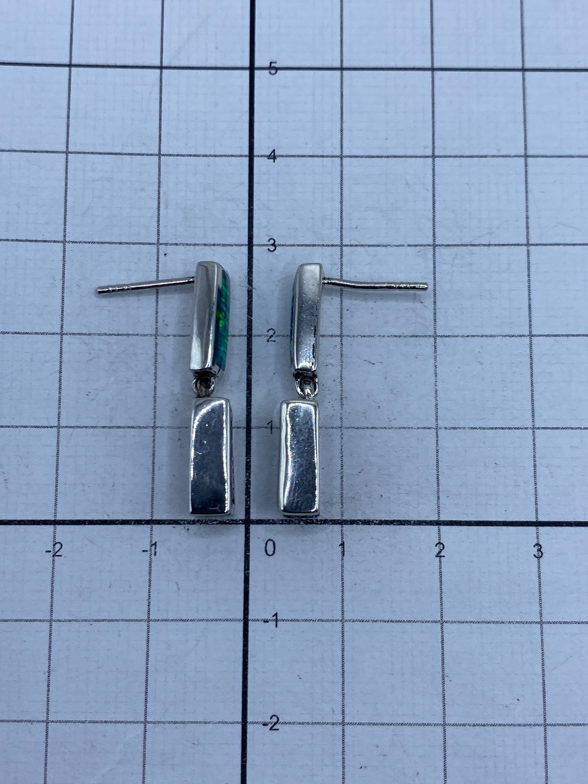 Los aretes de plata colocados sobre superficie gris, mostrando el Quinto 925