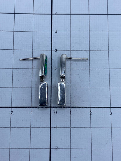 Los aretes de plata colocados sobre superficie gris, mostrando el Quinto 925