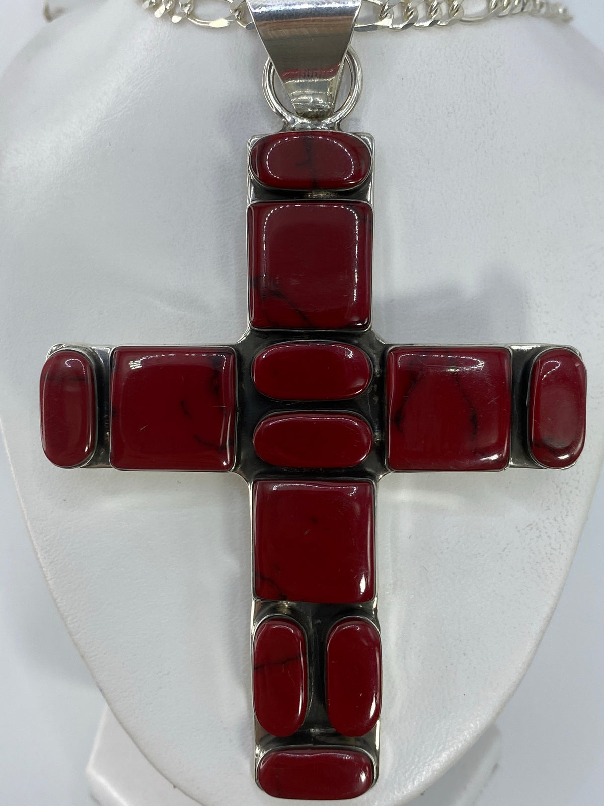 Dije cruz de plata 925 con piedra roja, hecho en Taxco, colgando de una cadena de plata
