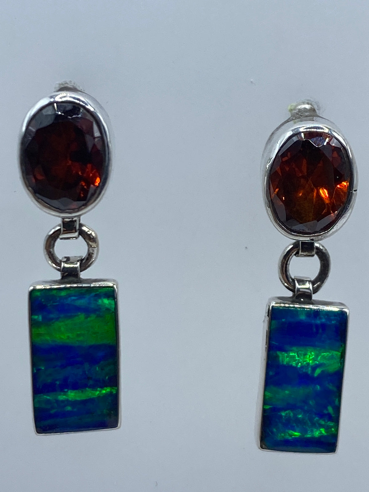 Aretes puestos en la oreja, ópalo azul reflejando luz natural