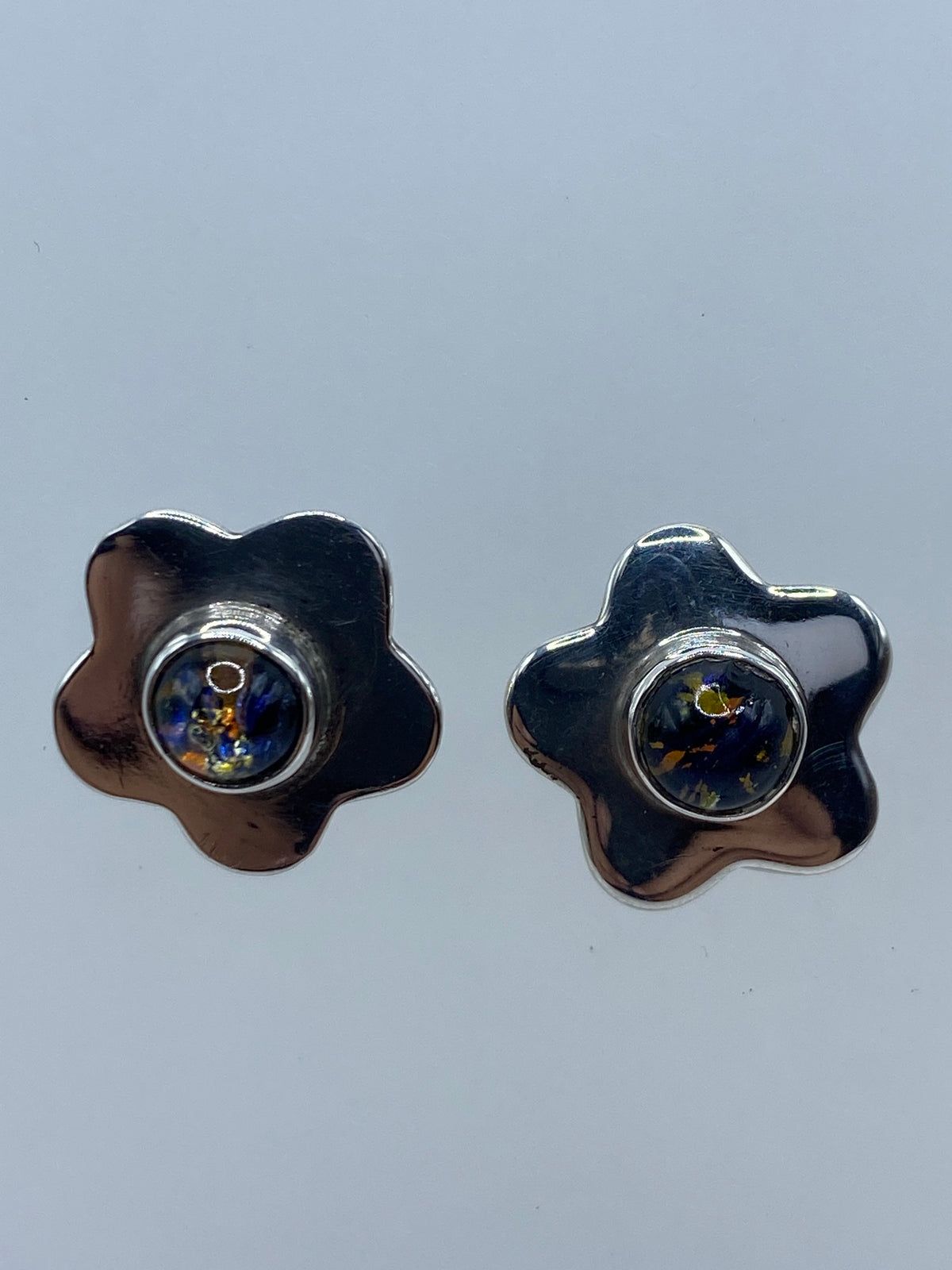 Par de aretes de plata flor pequeños en vista frontal, diseño minimalista