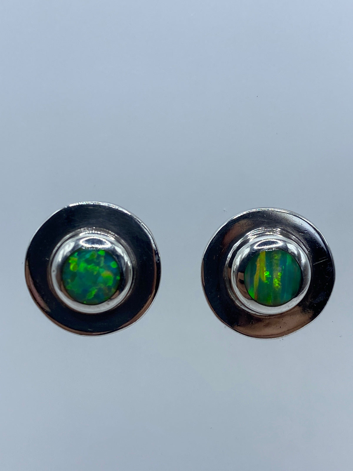 Par de aretes de plata con ópalo de fuego verde, 1.7 cm, sobre fondo neutro
