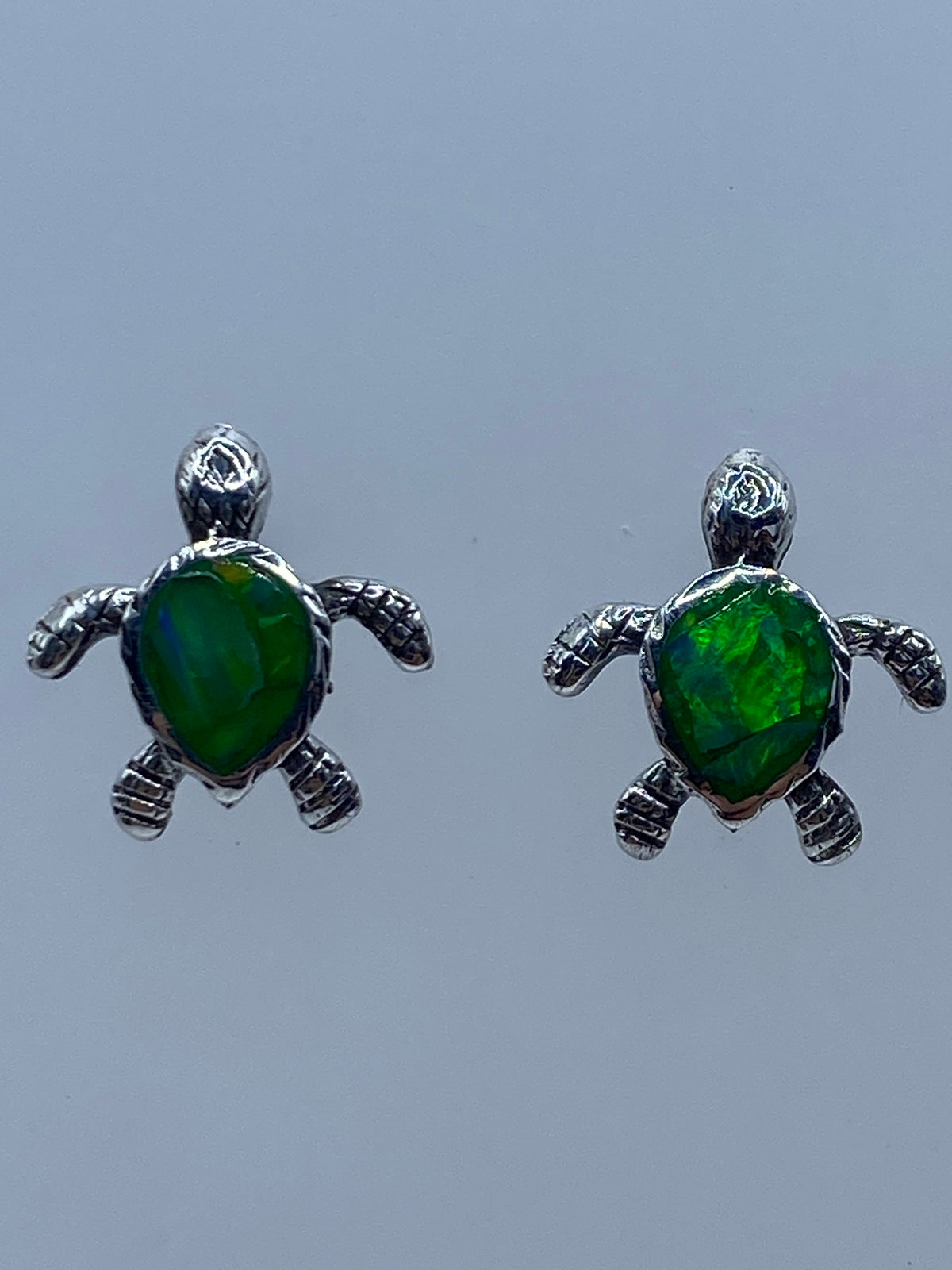 Par de aretes de plata tortuga con ópalo de fuego verde limón en fondo neutro