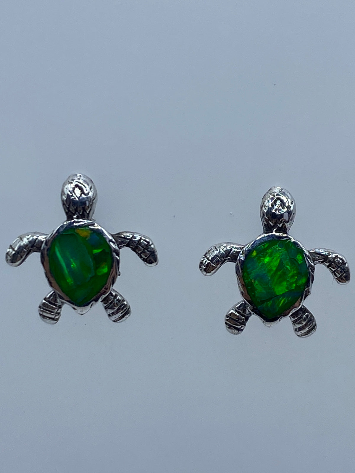 Detalle del engaste a mano del ópalo de fuego en los aretes de tortuga de Taxco