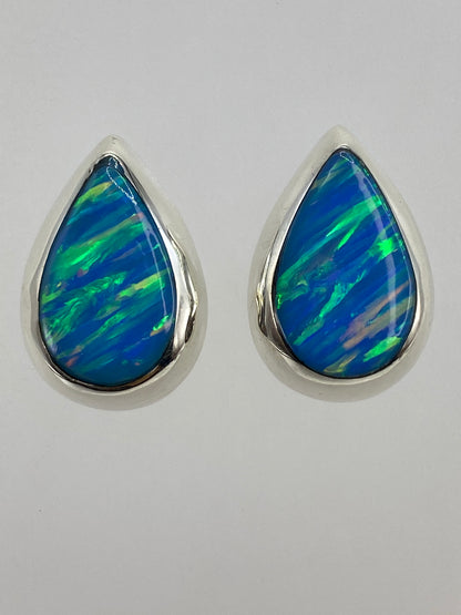 Aretes sobre regla de centímetros mostrando tamaño exacto 1.4 × 2 cm