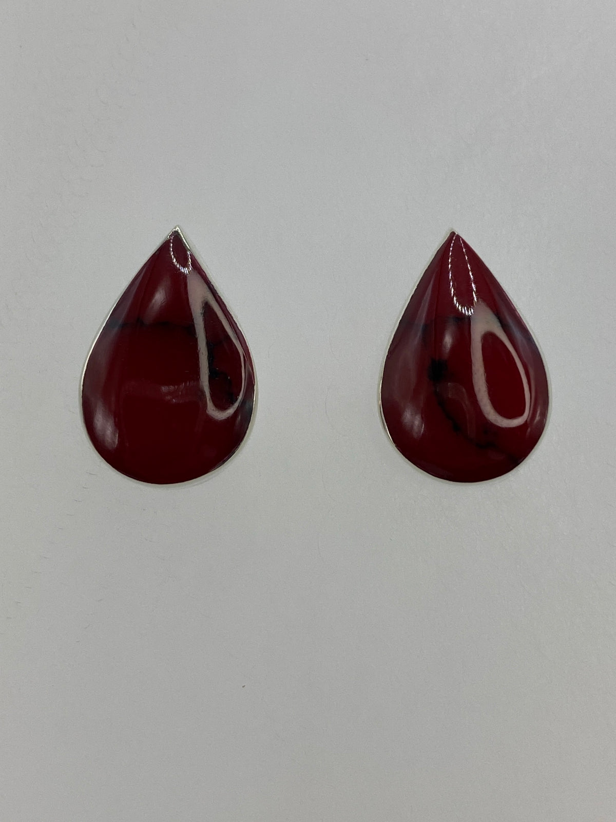 Par de aretes de plata con coral rojo engastado, vista frontal sobre fondo blanco
