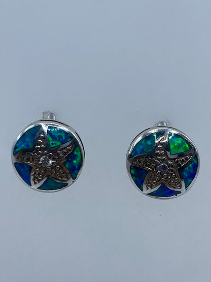 Par de aretes de plata con ópalo de fuego azul sobre fondo blanco
