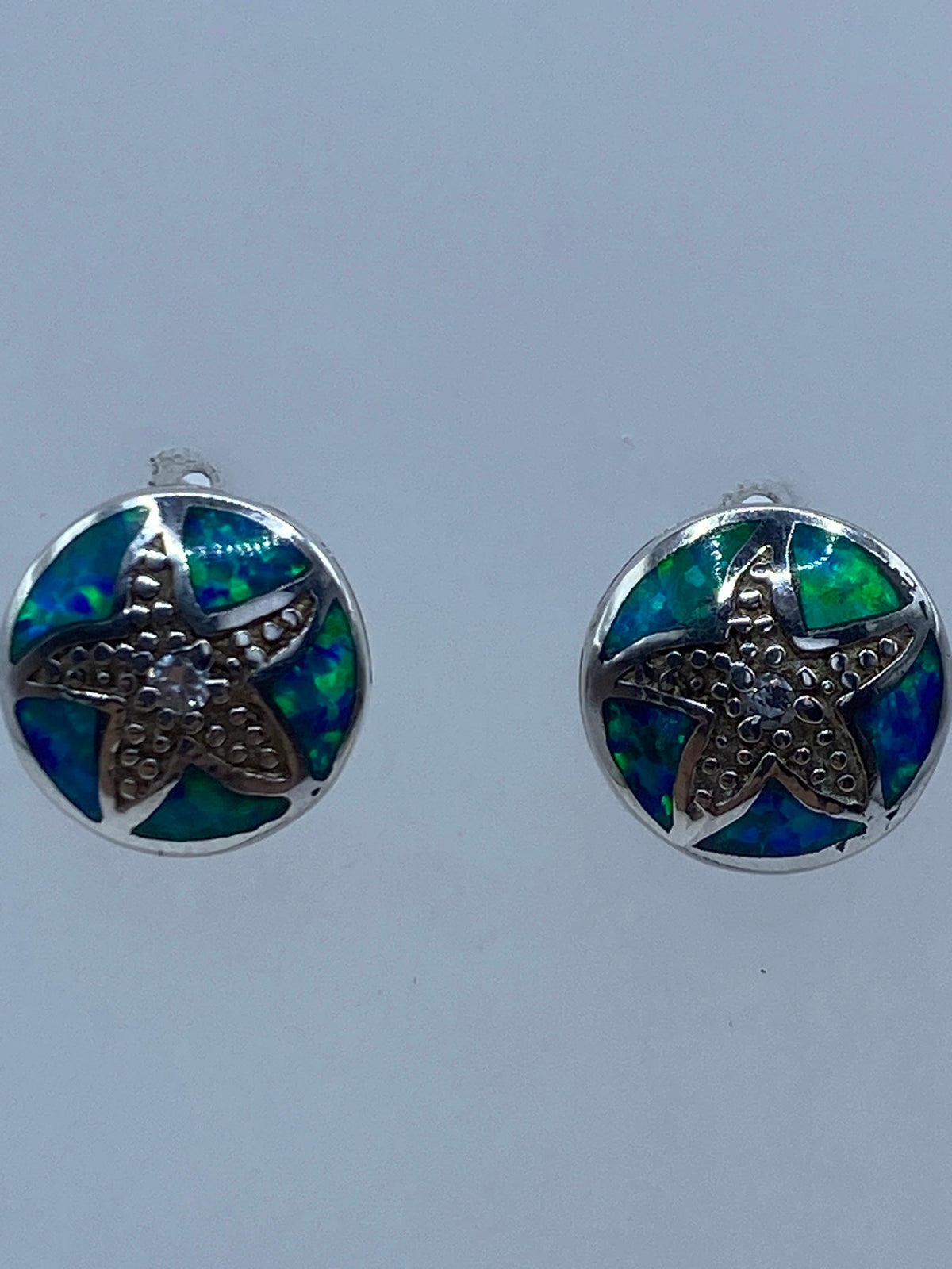 Aretes de ópalo de fuego azul vistos de frente mostrando el Quinto