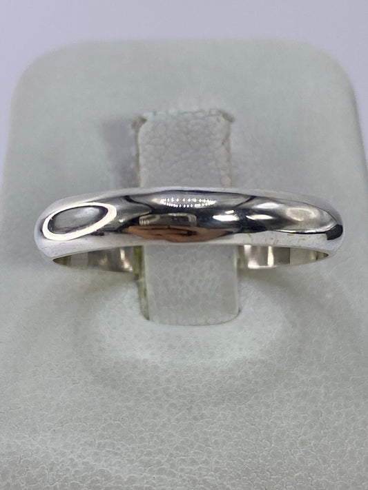 Anillo de plata pulido minimalista en mano de mujer, vista superior