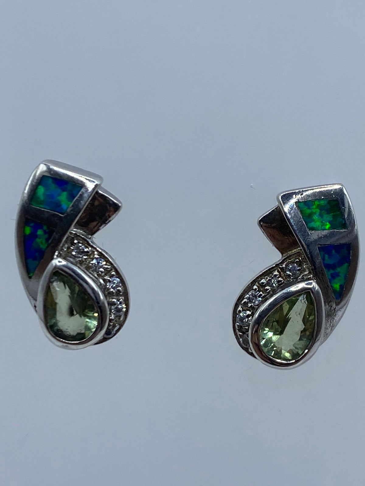 Vista frontal de aretes minimalistas ópalo azul contra fondo gris