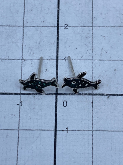 Aretes tortuga colocados sobre fondo blanco con postes de presión visibles