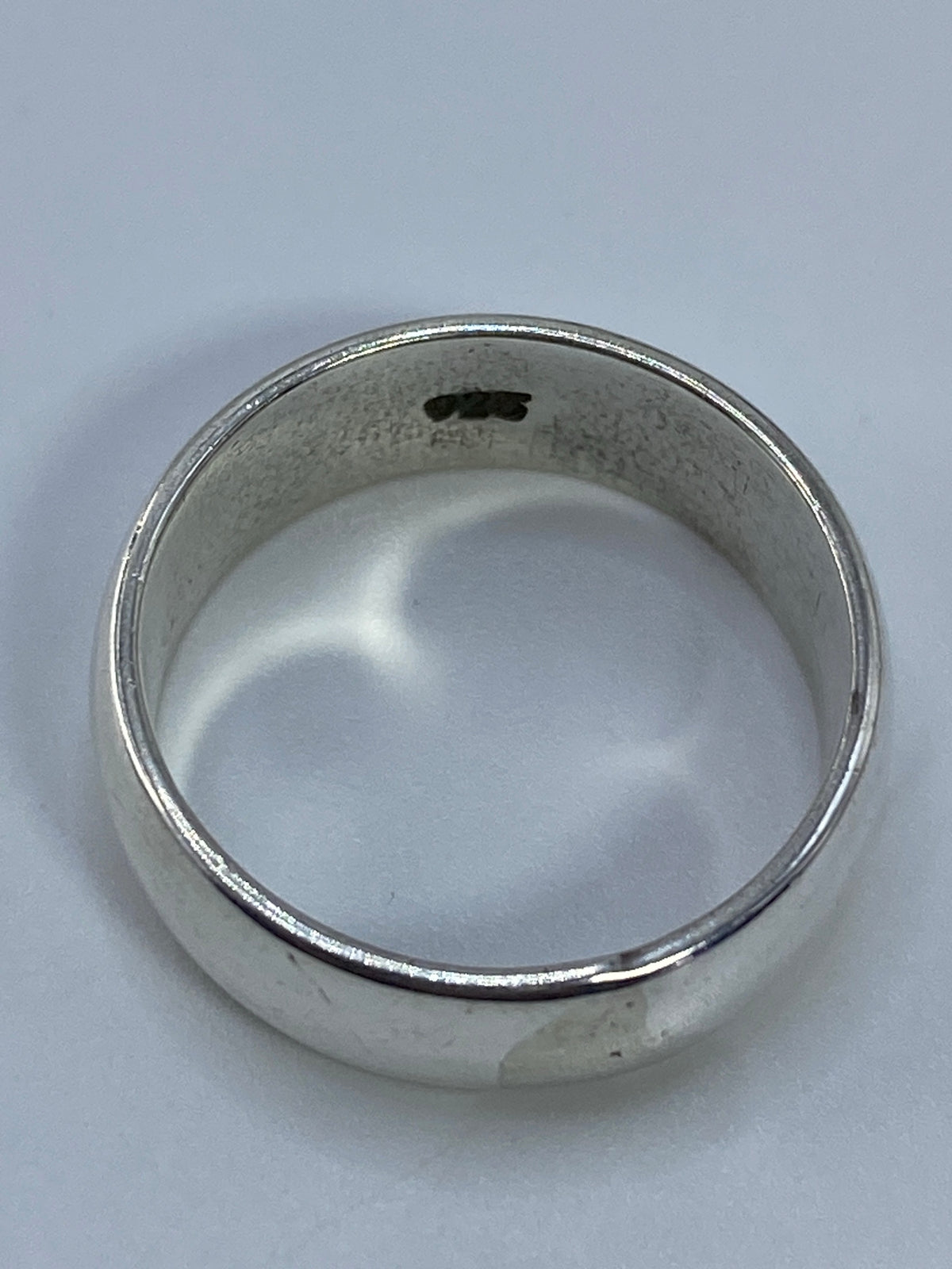 Detalle del anillo sobre fondo blanco, mostrando la pureza del metal y el pulido espejo