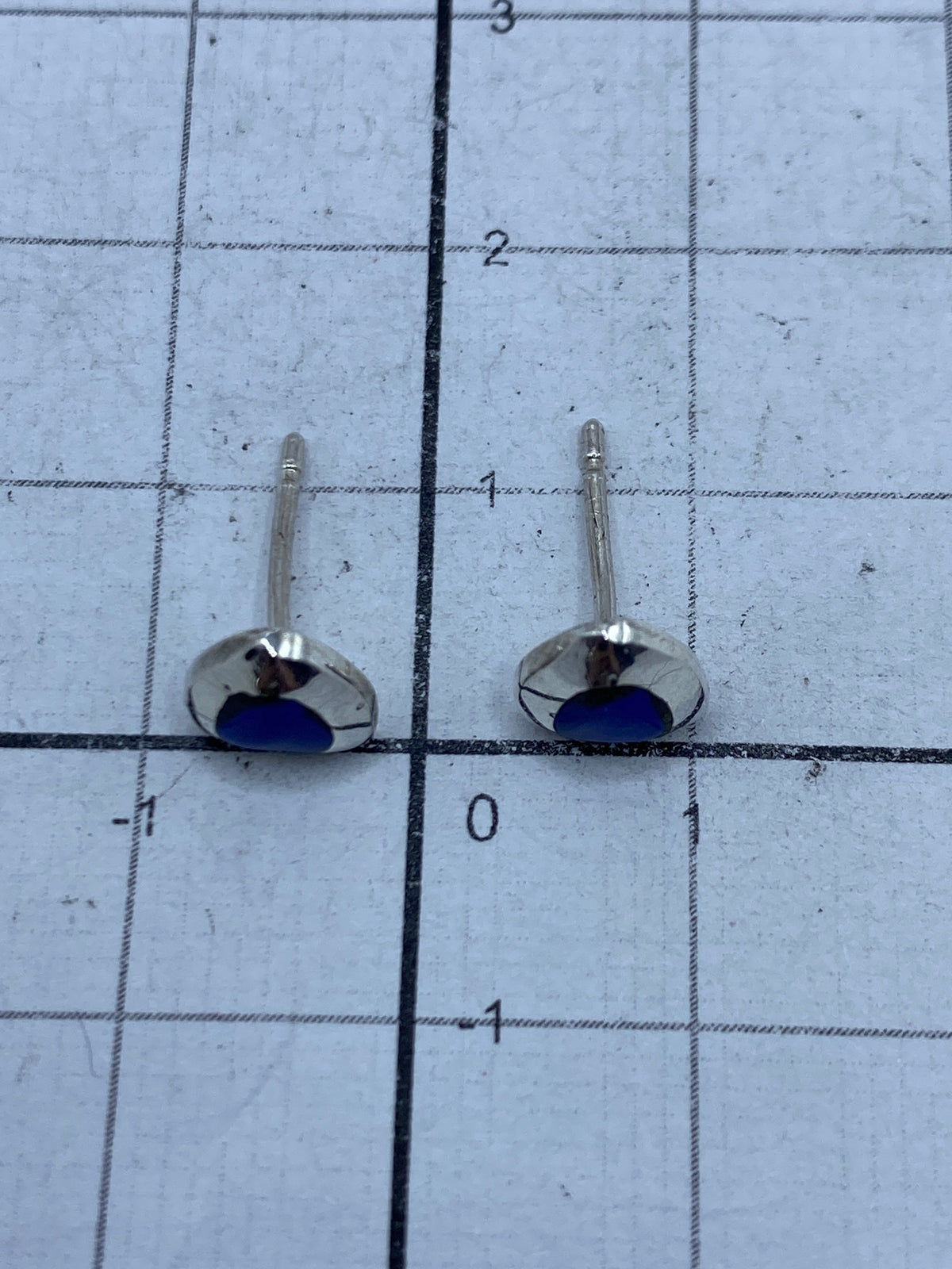 Aretes sobre fondo claro mostrando el engaste manual del lapislázuli