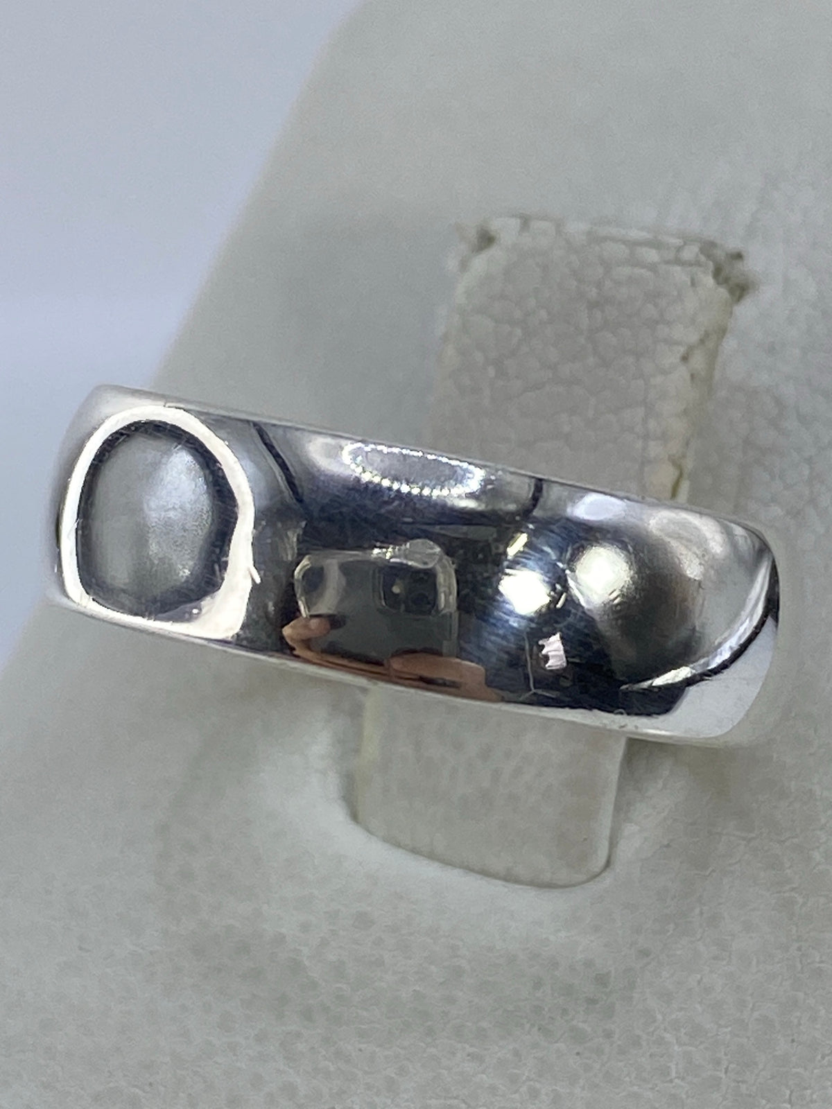 Detalle lateral del anillo de plata mostrando el acabado pulido y el brillo espejo