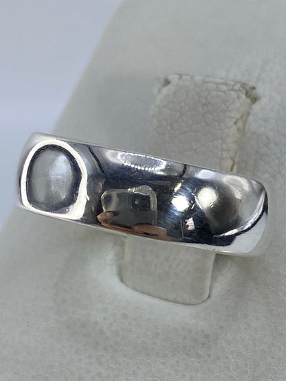 Detalle lateral del anillo de plata mostrando el acabado pulido y el brillo espejo