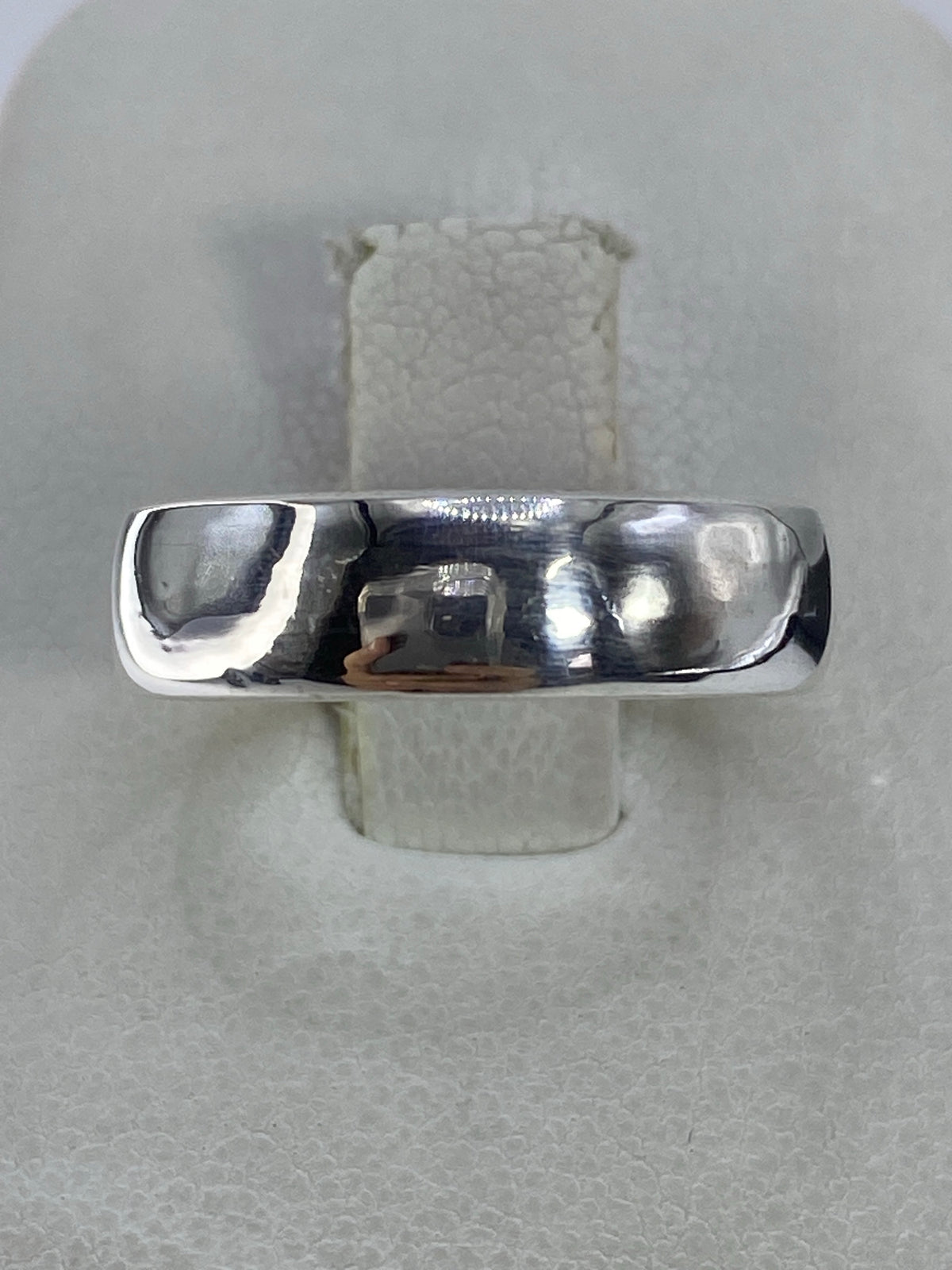 Anillo minimalista de plata 925 pulida sobre dedo, mostrando el acabado de espejo