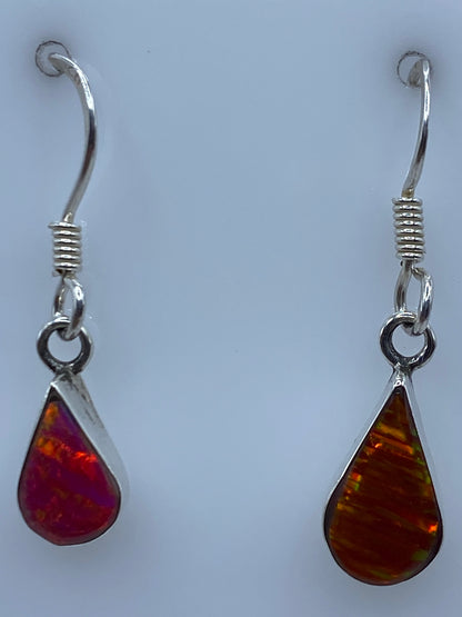 Aretes de plata ópalo de fuego sobre regla de medición mostrando 2.7 cm de largo