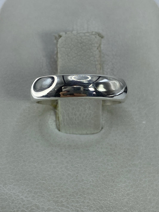 Anillo de plata pulida minimalista en talla 5, visto sobre banda de tela