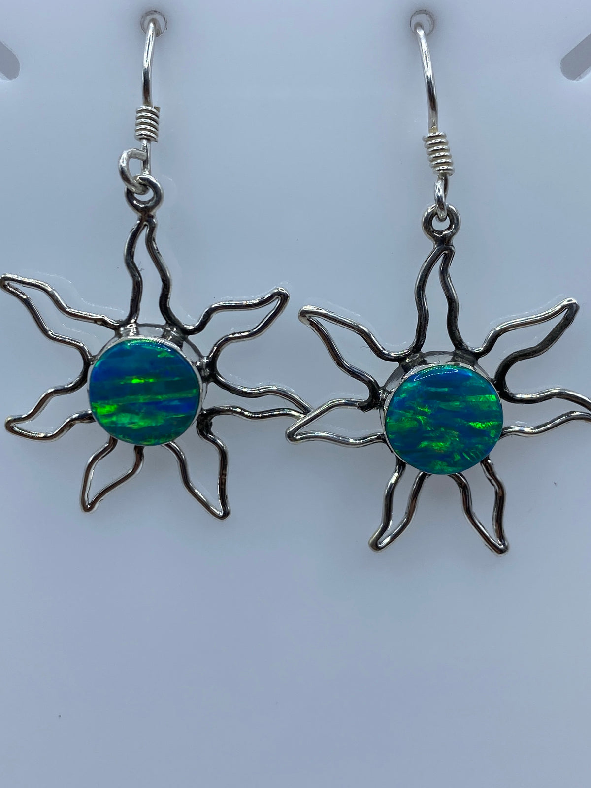 Par de aretes de plata con ópalo de fuego azul en forma de sol, mostrados juntos