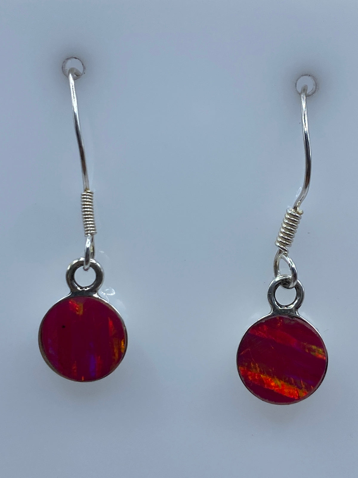 Par de aretes de plata con ópalo de fuego rosa, mostrando el juego de luz natural