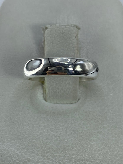 Anillo banda de plata pulida sobre dedo, vista frontal