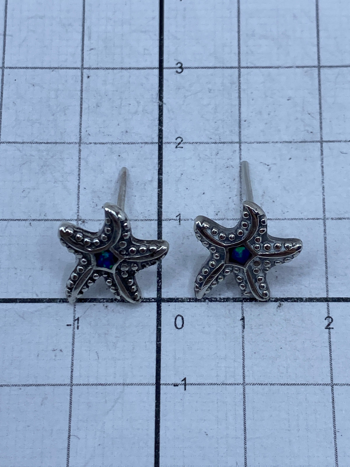 Aretes de plata con ópalo azul desde ángulo lateral