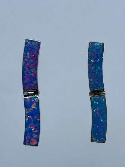 Par de aretes de plata 950 con ópalo de fuego azul, vistos de frente sobre fondo blanco