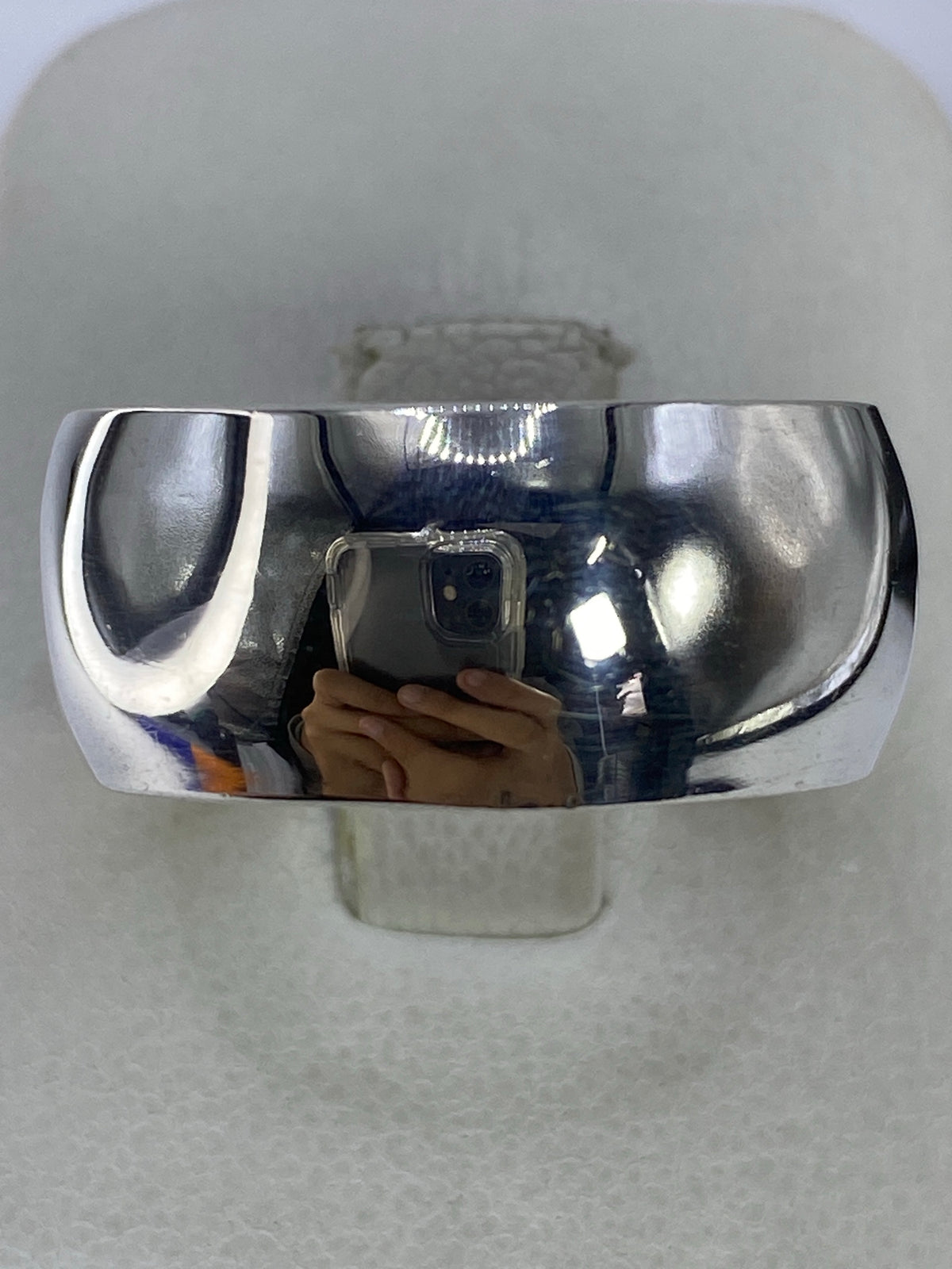 Anillo de plata espejo pulido visto de frente, reflejando luz