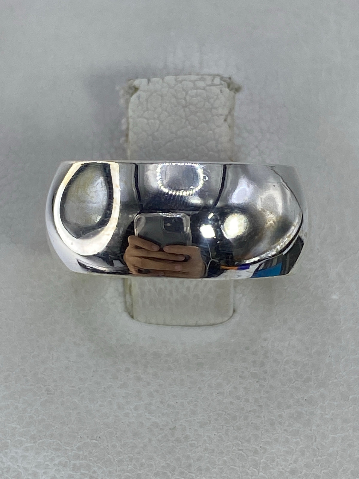 Anillo de plata 925 pulido minimalista visto desde arriba, reflejo espejo en superficie blanca