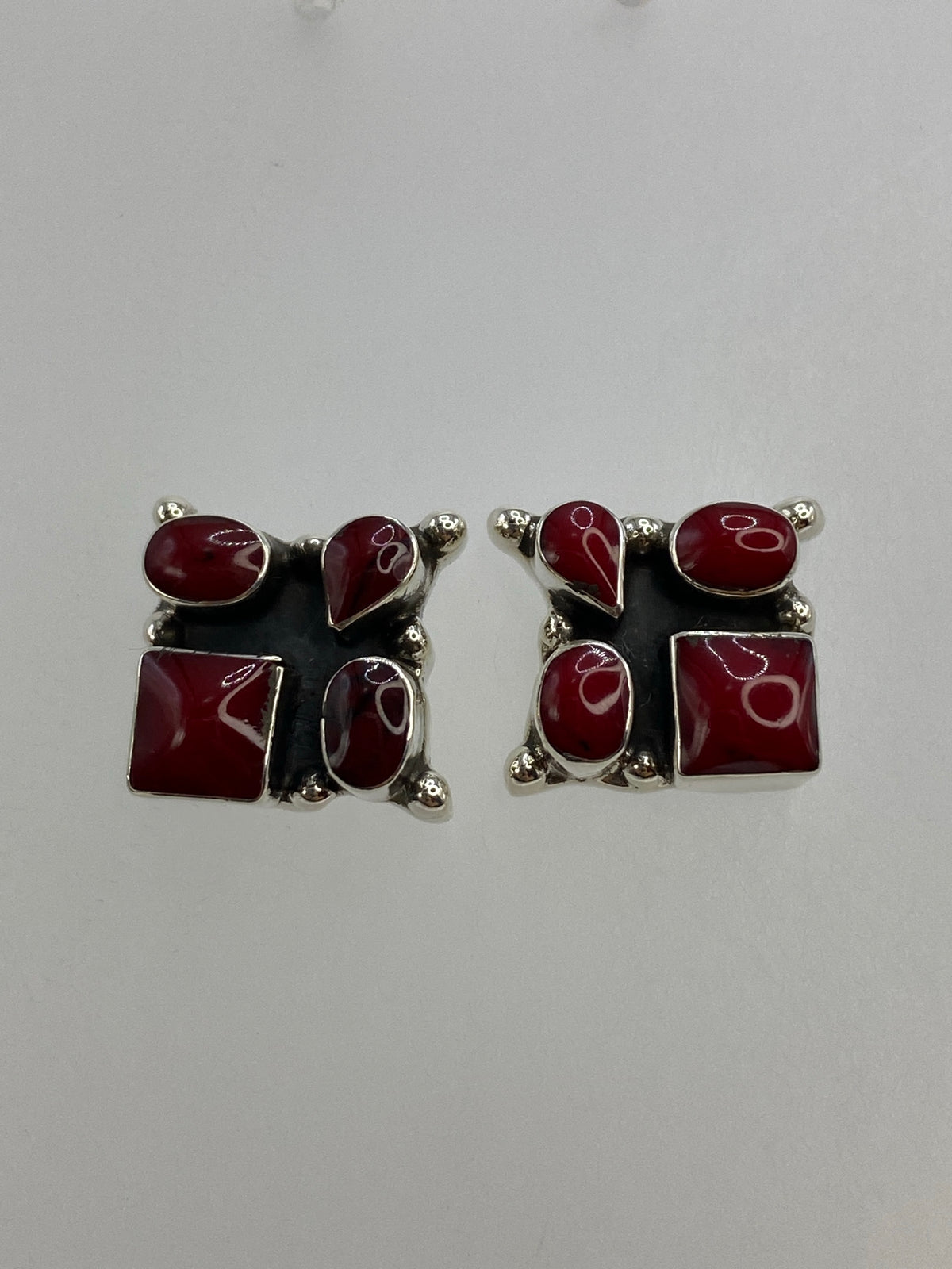 Par de aretes de plata con coral rojo engastado, sobre fondo blanco